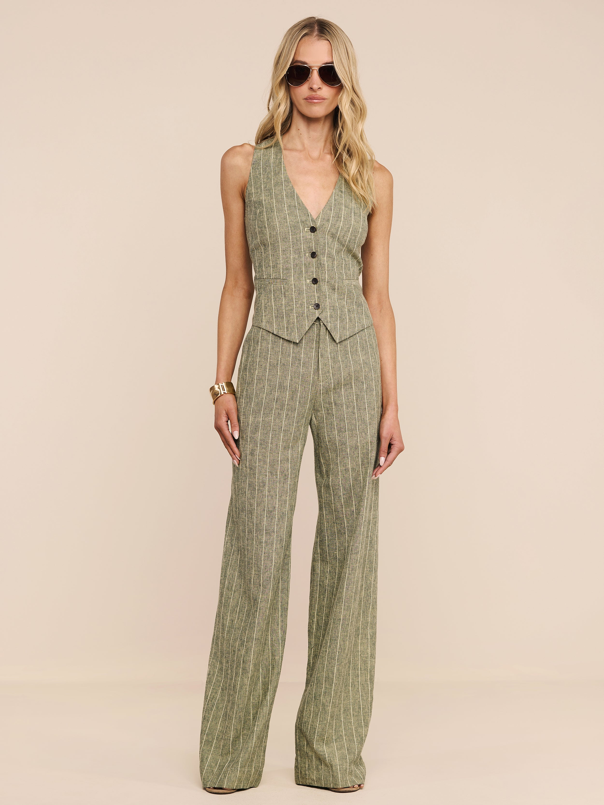 A woman wearing sunglasses, a sleeveless pinstriped vest, and the Livvy Linen-Blend Trouser stands against a plain white background.
