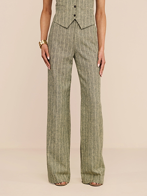 Portant le pantalon Livvy Linen-Blend - taille haute, jambe droite, à rayures gris-vert - une personne lassocie à un gilet assorti et à un bracelet en or, devant un fond beige uni.