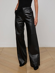 A person wearing the Livvy Leather Trouser—a pair of high-waisted, wide-leg black lambskin leather pants—with hands in pockets, paired with a black top, against a plain light background.