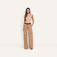 A woman wears a beige tank top and Livvy Suede Straight-Leg Trouser in light brown, secured with a brown belt featuring a gold buckle.