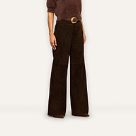 A person wearing a brown knit top, the Livvy Suede Trouser in a high-rise straight-leg silhouette, and a belt with a gold buckle stands against a plain background, capturing the essence of Fall 2026 style.