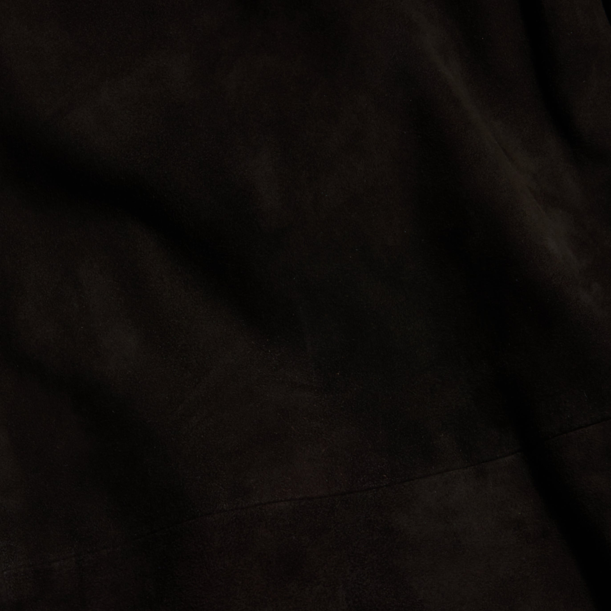 Close-up of a dark, textured fabric with subtle folds and shading, giving the surface a soft, velvety appearance reminiscent of the Livvy Suede Trouser for Fall 2026.