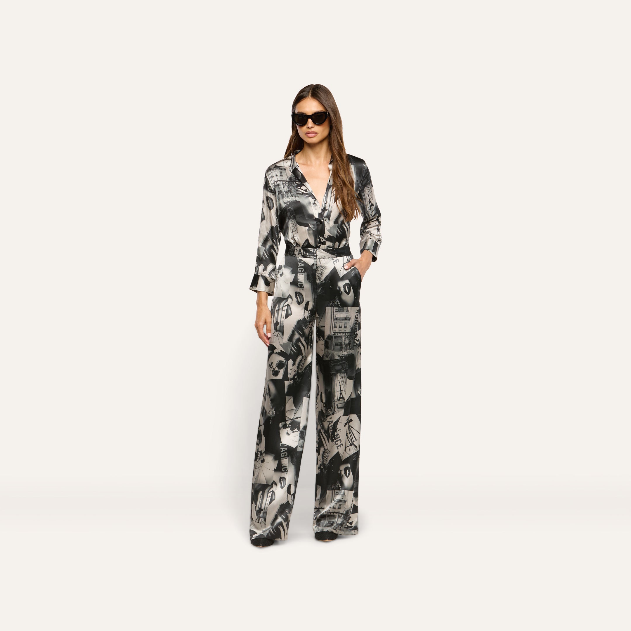 A woman wearing a matching button-down shirt and Livvy Silk Straight-Leg Trouser in a black-and-white magazine print with sunglasses.