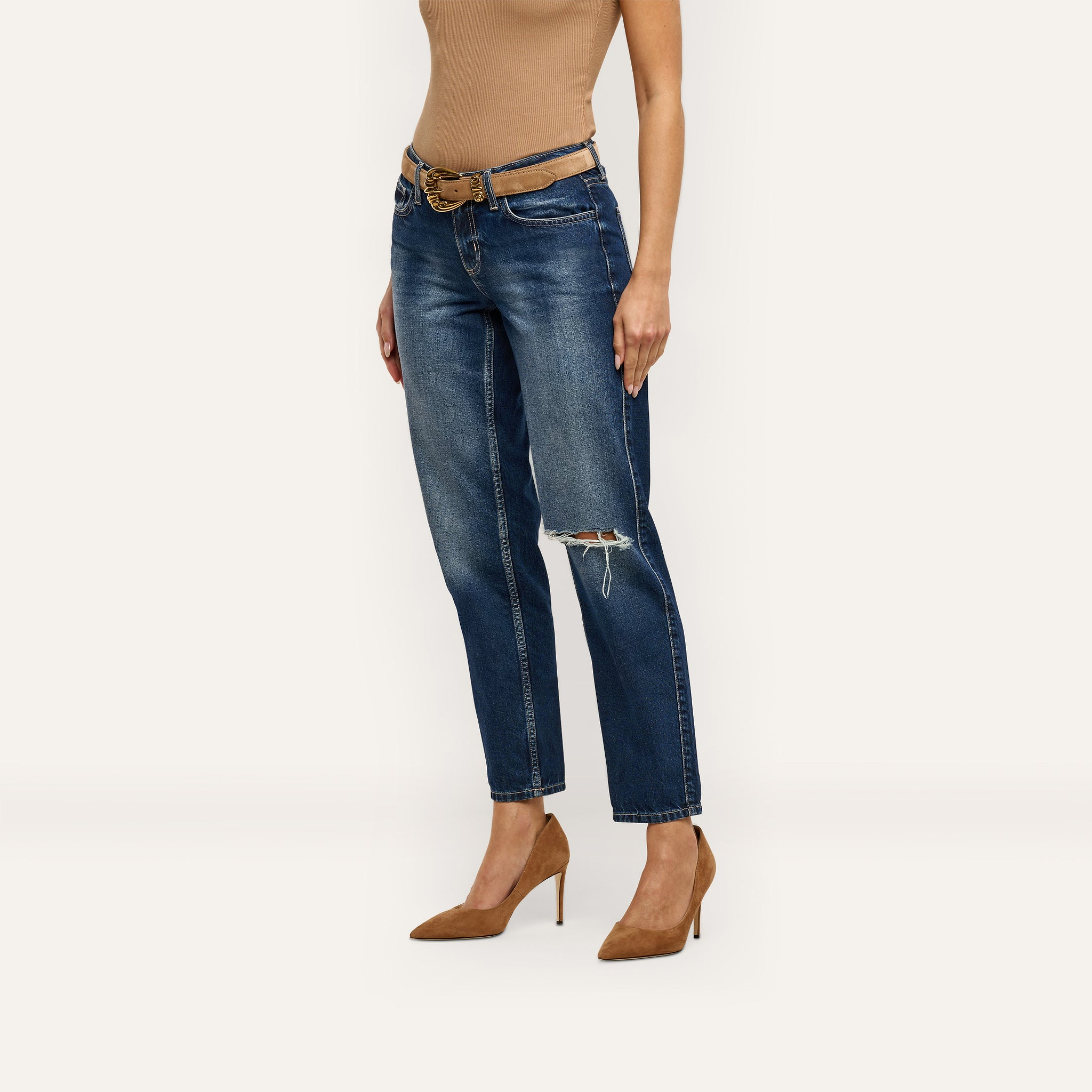 Nevia Slouchy Straight-Leg Jeans in an indigo wash with a distressed knee, worn with a tan belt and brown suede pumps.