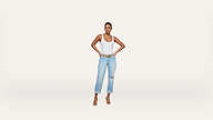 A woman stands against a plain white background, wearing a white tank top, light blue ripped jeans, a yellow belt, and heeled sandals, with her hands on her hips.