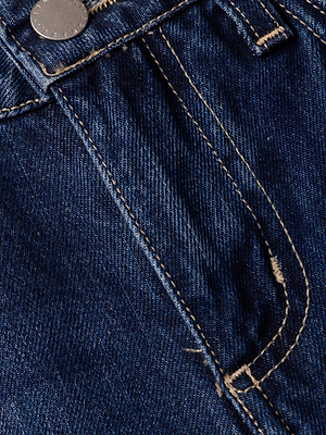 Close-up of the Nevia Slouchy Straight-Leg Jean pocket in dark blue vintage denim with orange stitching, a silver metal rivet, and textured fabric showing subtle fading and seam distressing.