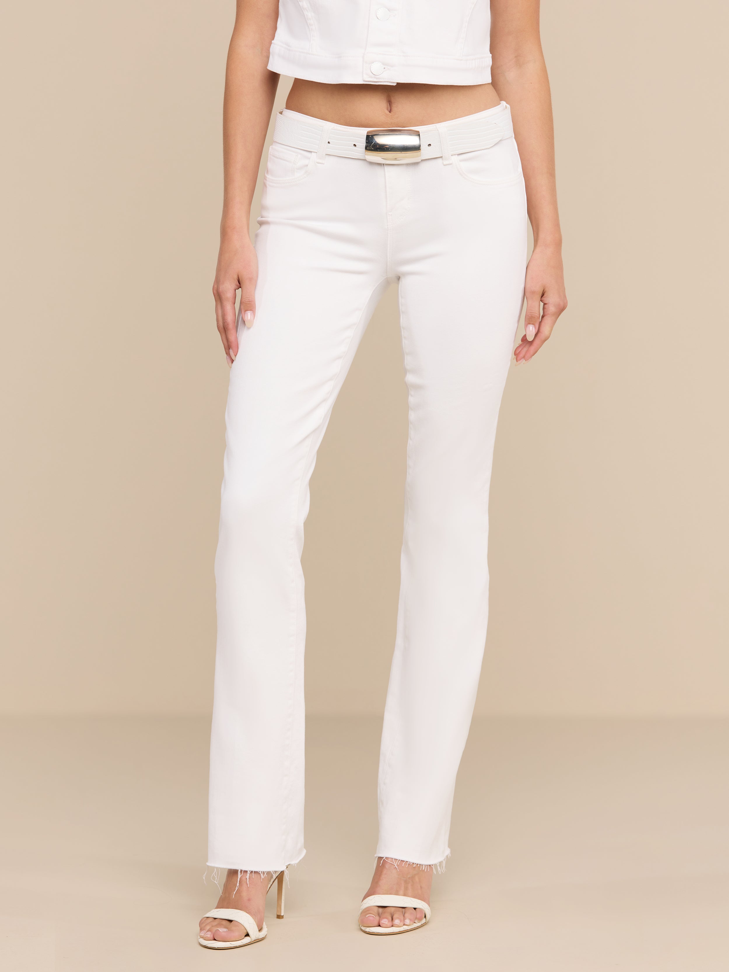 A person wearing the Sneeki Low-Rise Straight-Leg Jean, a white cropped top, and heeled sandals stands against a plain white background. Only the lower half of their body is visible.