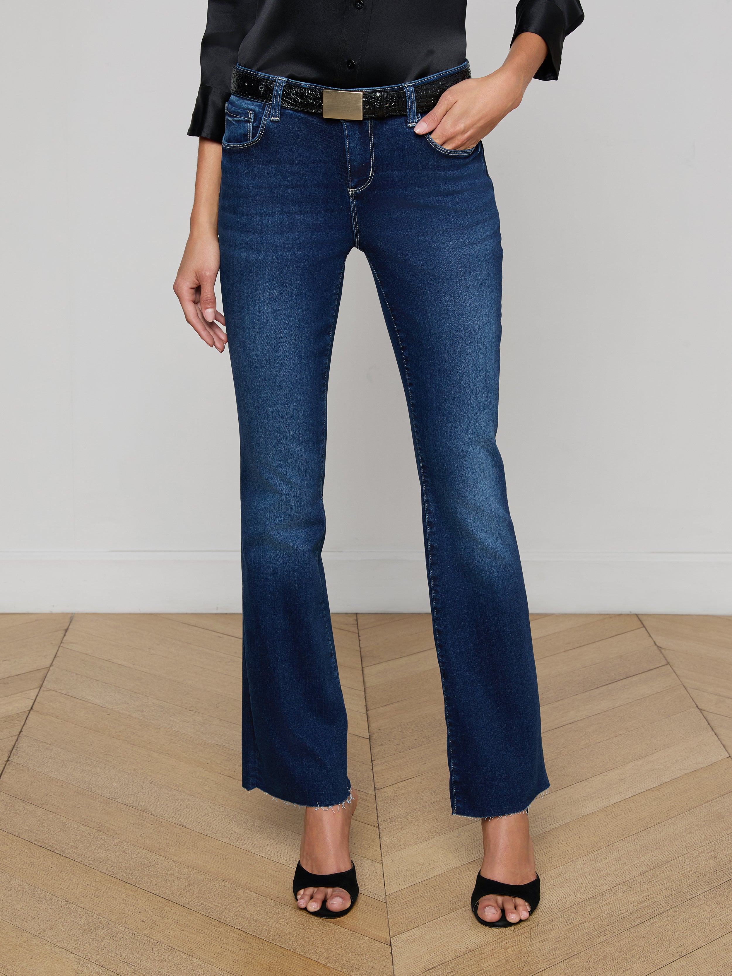 A person wearing a black sleeveless top, the Sneeki Low-Rise Straight-Leg Jean in a dark wash with a black belt, and black open-toe heels stands against a plain white background.