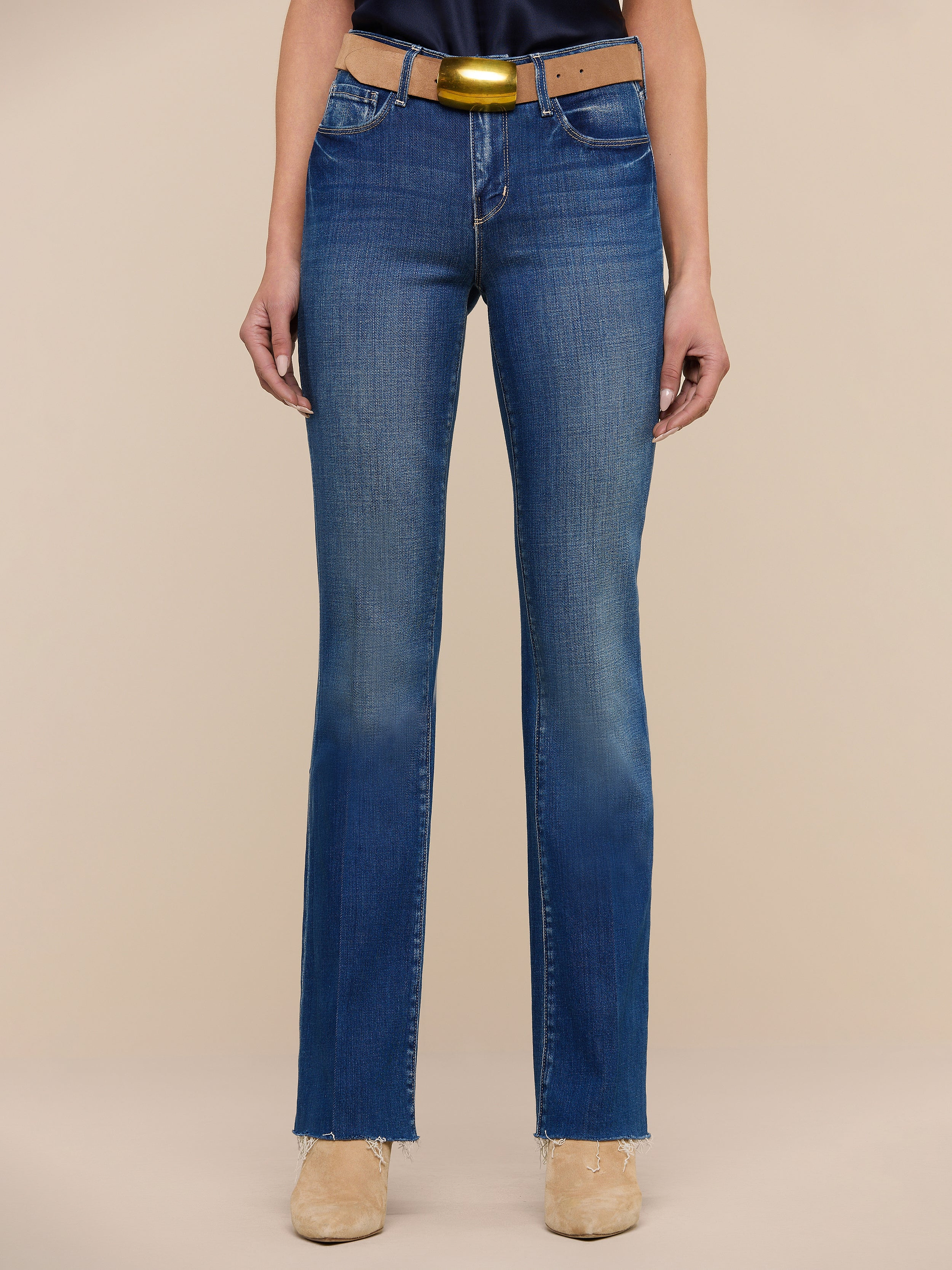 A person wearing Sneeki Low-Rise Straight-Leg Jeans in blue, paired with a brown belt and beige shoes, is standing against a plain white background. Only the lower half of the body is visible.