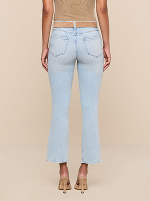 A person wearing the Tati Cropped Micro Boot Jean and beige heeled sandals is shown from the back against a plain beige background, paired with a sheer beige top.