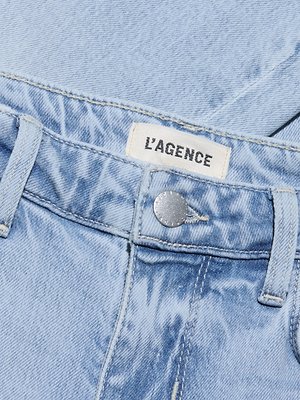Close-up of the Tati Cropped Micro Boot Jean in light wash denim, showing a metal button, belt loops, and a white L’AGENCE label in black lettering.
