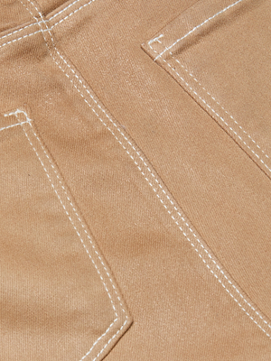 Close-up of the back pockets on the Tati Coated Bootcut Jean, featuring light brown leather-look stretch denim, white stitching detail, and part of the waistband.
