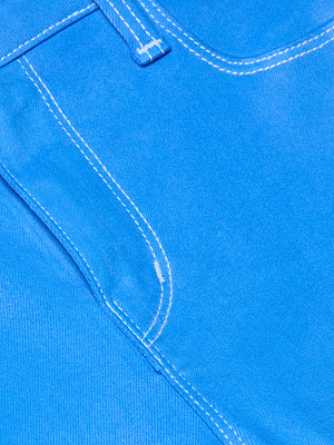Close-up of the bright blue Tati Coated Bootcut Jean, featuring a pocket and seam with white stitching that highlights the textured finish and detailed construction.