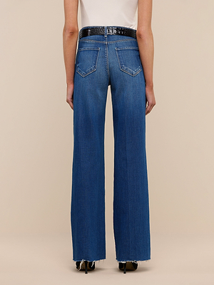 A person is shown from the back against a beige background wearing Scottie Wide-Leg Jeans in vintage-wash denim with frayed hems, paired with a black textured belt and black shoes.