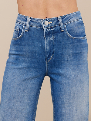 A close-up of a person wearing the Scottie Wide-Leg Jean, featuring high-rise blue denim with visible belt loops, front button, and pockets while exposing their midriff.