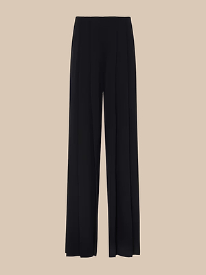 The Nova Pleated Wide-Leg Pant features a tailored black design with a high waist and pleated front, showcased on a plain beige background.