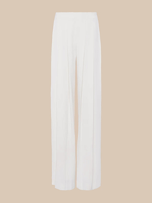 The Nova Pleated Wide-Leg Pant features a flattering high rise, ivory color, and long flowing legs, displayed on a plain beige background.