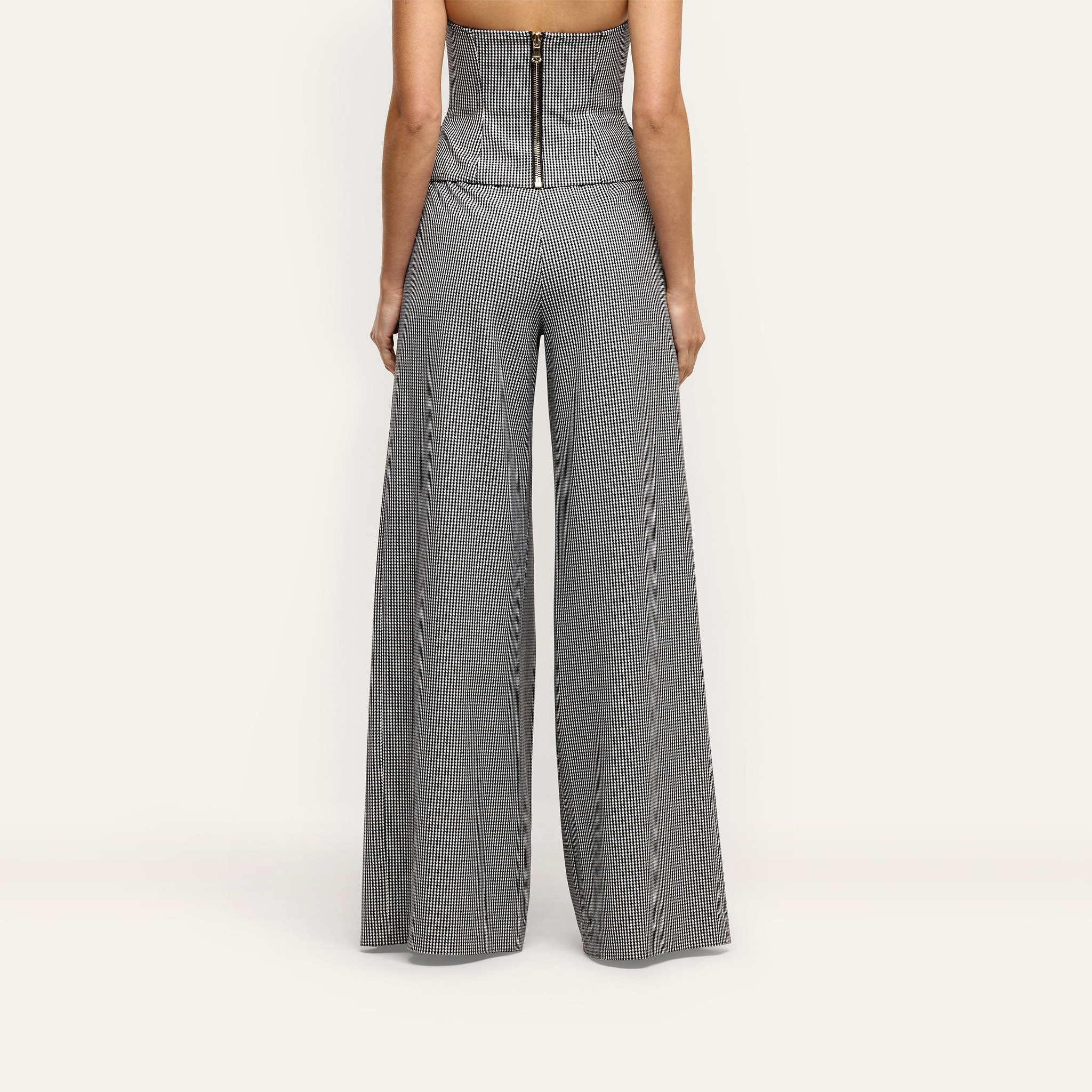 Rear view of a person wearing a black and white houndstooth corset top and matching Nova Pleated Wide-Leg Pant in suiting fabric.