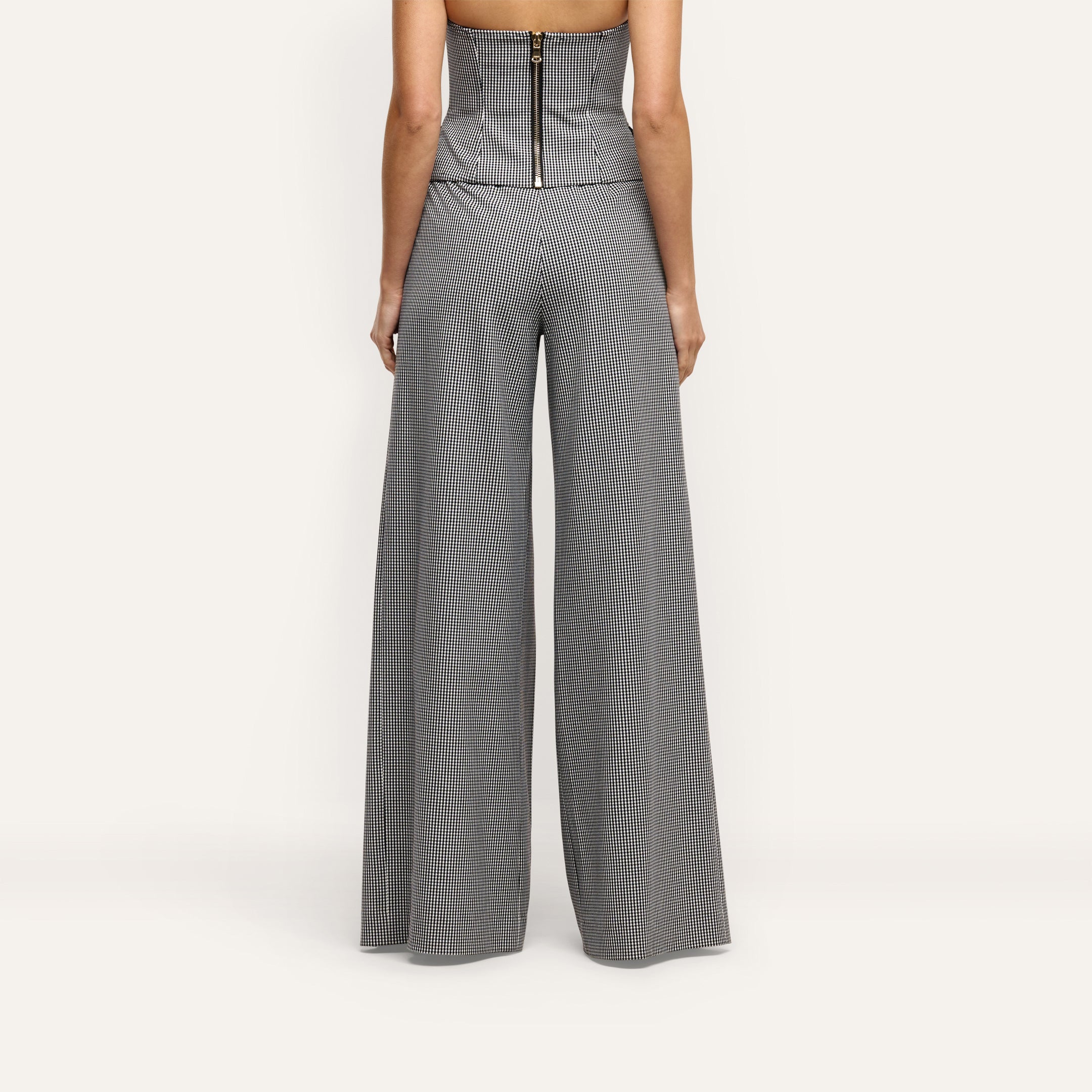 Rear view of a person wearing a black and white houndstooth corset top and matching Nova Pleated Wide-Leg Pant in suiting fabric.