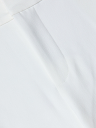 Close-up of the Allanah Trouser in white stretch fabric, featuring a visible seam and subtle texture that highlight its modern design details.