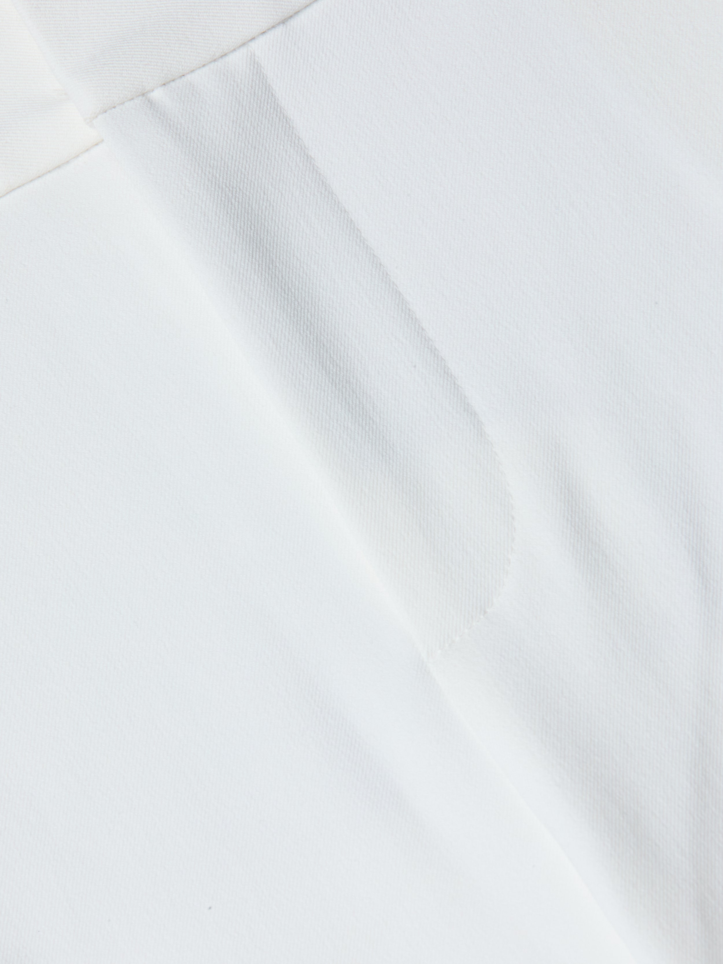 Close-up of the Allanah Trouser in white stretch fabric, featuring a visible seam and subtle texture that highlight its modern design details.