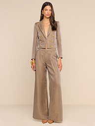 A woman stands against a plain white background wearing the Allanah Linen-Blend Trouser paired with a matching tan double-breasted blazer featuring gold buttons. She accessorizes with gold earrings, a gold bracelet, and pointed-toe heels, and wears her long hair down.