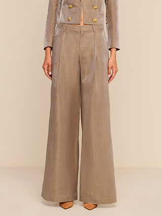 A person wearing the Allanah Linen-Blend Trouser in a wide-legged, high-waisted silhouette in latte brown linen blend fabric. Only the lower half of their body is visible.