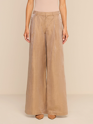 Wearing the Allanah Linen-Blend Trouser in high-waisted, wide-leg latte brown, paired with a beige sleeveless top and brown heeled shoes, a person stands against a beige background.