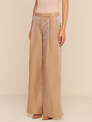Wearing the Allanah Linen-Blend Trouser in a high-waisted, wide-leg silhouette and beige pointed-toe heels, the person stands against a plain beige background.