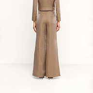 A person stands facing away, wearing a taupe-colored, tailored suit featuring the Allanah Linen-Blend Trouser with wide-leg styling and a matching blazer, set against a plain white background.