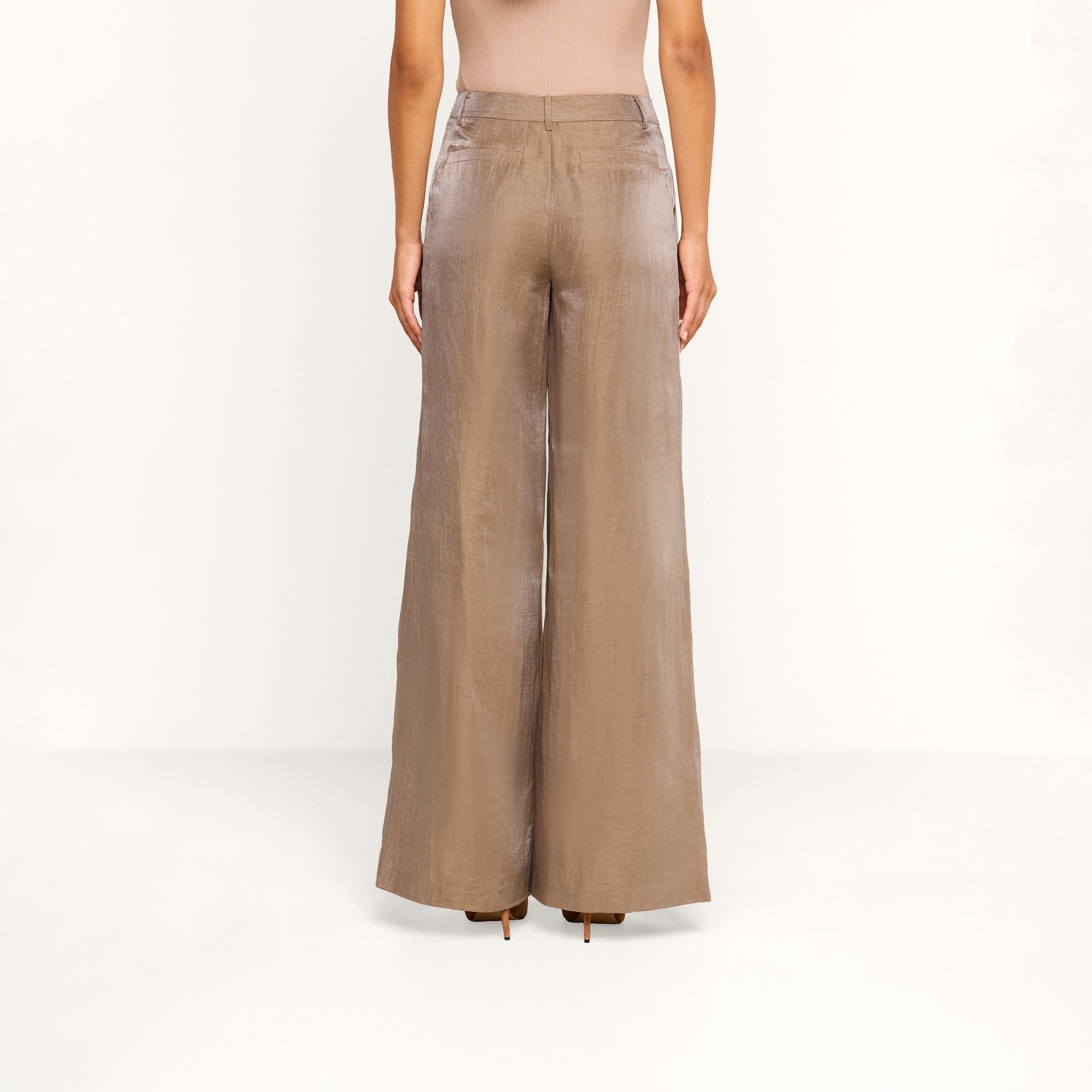 A person stands facing away, wearing the Allanah Linen-Blend Trouser in latte brown with a beige sleeveless top against a plain white background.