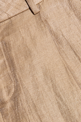 Close-up of light brown, shimmery fabric with subtle wrinkles and a seam, likely part of the Allanah Linen-Blend Trouser. The texture and sheen suggest a comfortable yet stylish linen-blend material, perfect for flattering fit trousers in a lightweight latte brown shade.