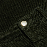 Close-up of the Scottie Corduroy Pant in dark green, featuring a high-rise, wide-leg silhouette with a metallic button at the waistband that highlights the fabric’s rich ribbed texture and detailed edging—an elevated choice for fall 2026 fashion.