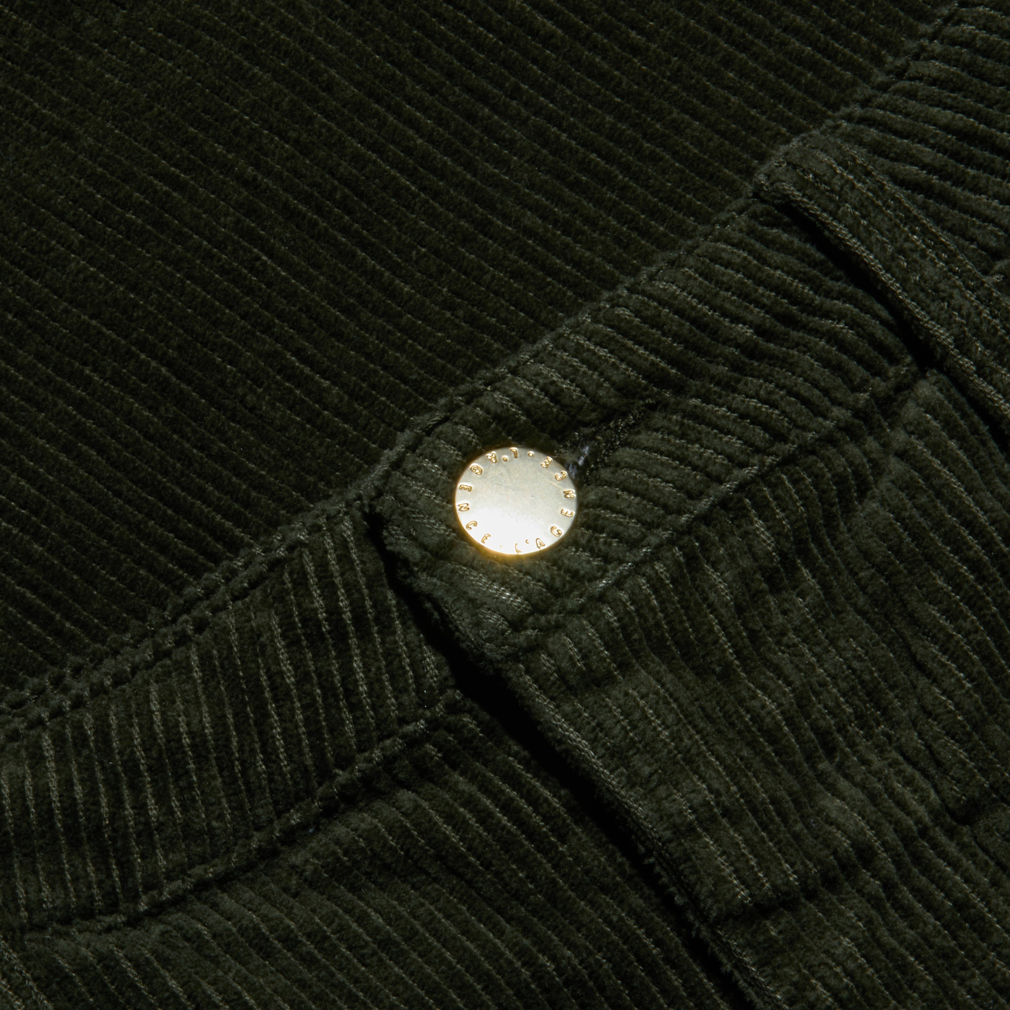 Close-up of the Scottie Corduroy Pant in dark green, featuring a high-rise, wide-leg silhouette with a metallic button at the waistband that highlights the fabric’s rich ribbed texture and detailed edging—an elevated choice for fall 2026 fashion.