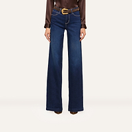 A person wearing high-waisted, wide-leg blue jeans and a brown long-sleeve blouse styled with a brown belt featuring a gold buckle and brown heeled boots stands confidently against a white background.