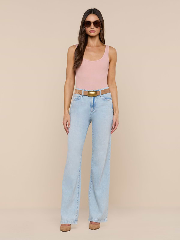 A woman stands against a plain white background wearing sunglasses, a pink tank top, brown shoes, and the Scottie Wide-Leg Jean in a light wash high-rise style with a belt.