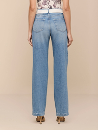 Eine Person schaut weg und trägt die Scottie Wide-Leg Jeans - eine hoch geschnittene Jeans aus reiner Baumwolle mit Gesäßtaschen und einem ärmellosen Oberteil mit Blumenmuster. Die entspannte Passform mit geradem Bein und beigefarbenen Schuhen sorgt für einen schicken, lässigen Stil.