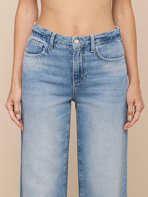 A person wears Scottie Wide-Leg Jeans in light blue, featuring high-rise all-cotton denim with button and zipper closure. Only their torso and upper legs are visible as their hands rest at their sides.