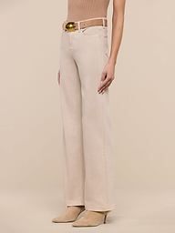 A person wearing the Scottie Wide-Leg Jean in beige—crafted from premium stretch denim and featuring a high-rise, wide-leg silhouette—is styled with a matching beige belt and tan pointed-toe heels, standing against a plain white background. The upper body and head are not visible.