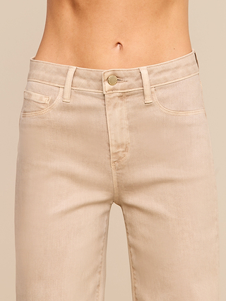 A close-up of a persons waist and legs wearing the Scottie Coated Wide-Leg Jean in beige, featuring a high rise, button closure, front pockets, and belt loops, set against a neutral background.