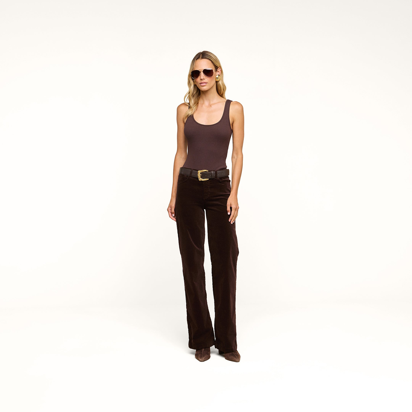 A woman in sunglasses wears a brown tank top and the Scottie Velvet Wide-Leg Jean with a contoured waistband, paired with brown shoes, standing against a plain white background.