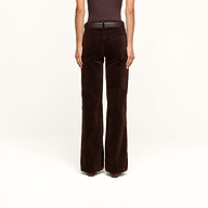 A person stands facing away, wearing a sleeveless brown top paired with the Scottie Velvet Wide-Leg Jean, featuring a contoured waistband and a black belt, set against a plain white background.