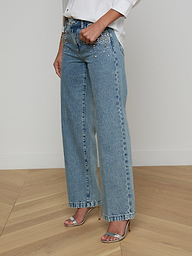 Model wearing the Scottie Embellished Wide-Leg Jean in light blue all-cotton denim with pearl detailing, paired with a white shirt and silver high-heeled sandals, shown from shoulders down against a plain background.
