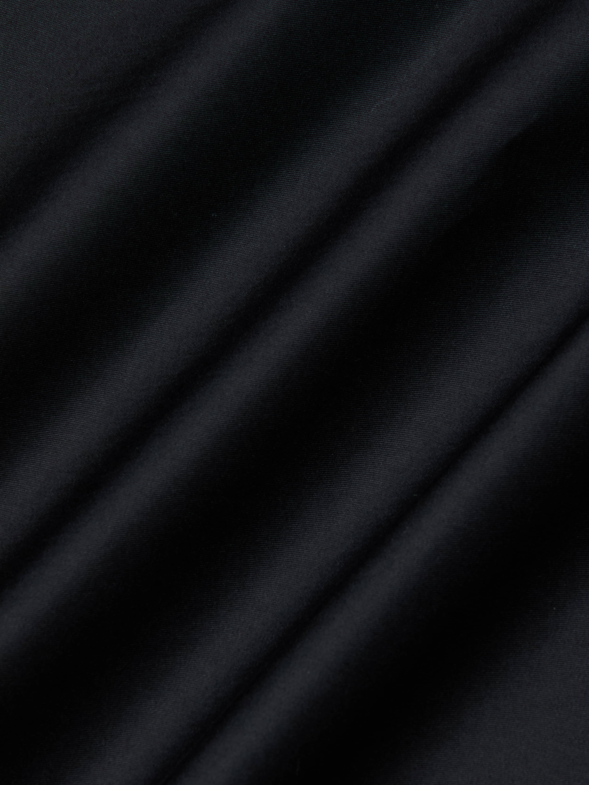 Close-up of the Lowen Pant’s black poplin fabric, featuring diagonal, soft shadows and a subtle texture that creates a striped pattern across the surface.