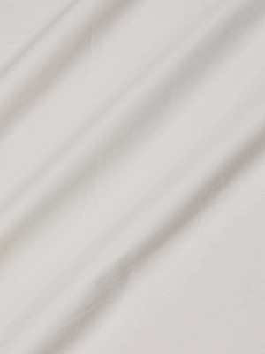 A close-up of the Lowen Pant by L'AGENCE showcases vintage white fabric with soft, diagonal folds and gentle shadows that highlight its textured appearance.