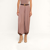 A person wearing the Palmer Satin Pant—a loose, mauve high-rise balloon trouser styled with a dark belt—paired with a taupe sleeveless top and beige heeled boots, stands against a white background.