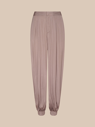 The Palmer Satin Pant in light mauve features a high rise, pleated front, button and zip closure, and gathered elastic cuffs at the ankles, showcased against a plain beige background.