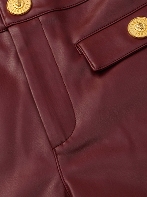 Close-up of the Dionne Vegan Leather Short in black cherry, showcasing gold embossed buttons, a flap pocket, and visible leather texture with detailed stitching.
