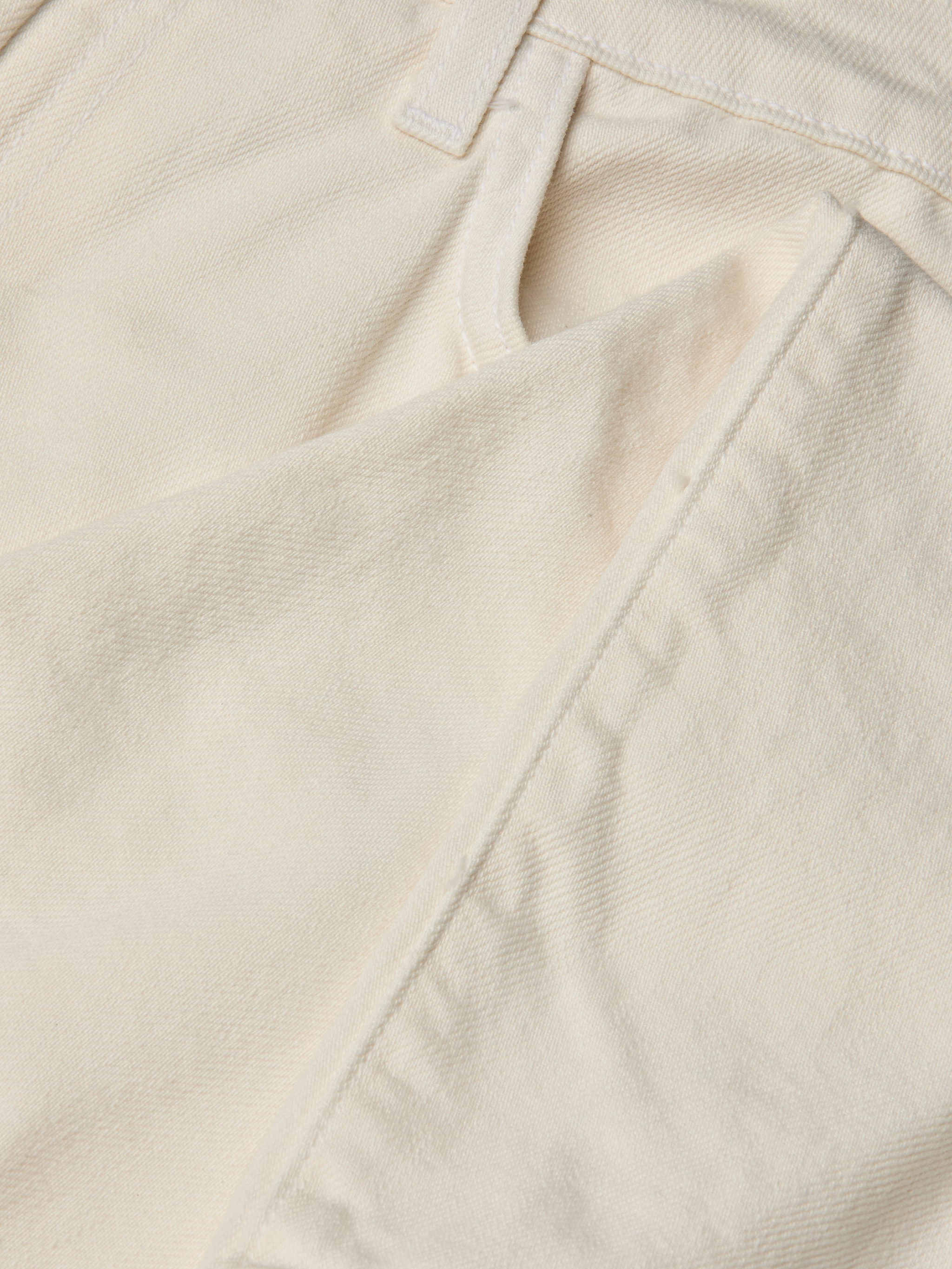 Close-up of the front pocket and waistband of the Blaine Cropped Stovepipe Jean in cream-colored all-cotton denim, highlighting the fabric’s texture, precise stitching, and part of a belt loop.