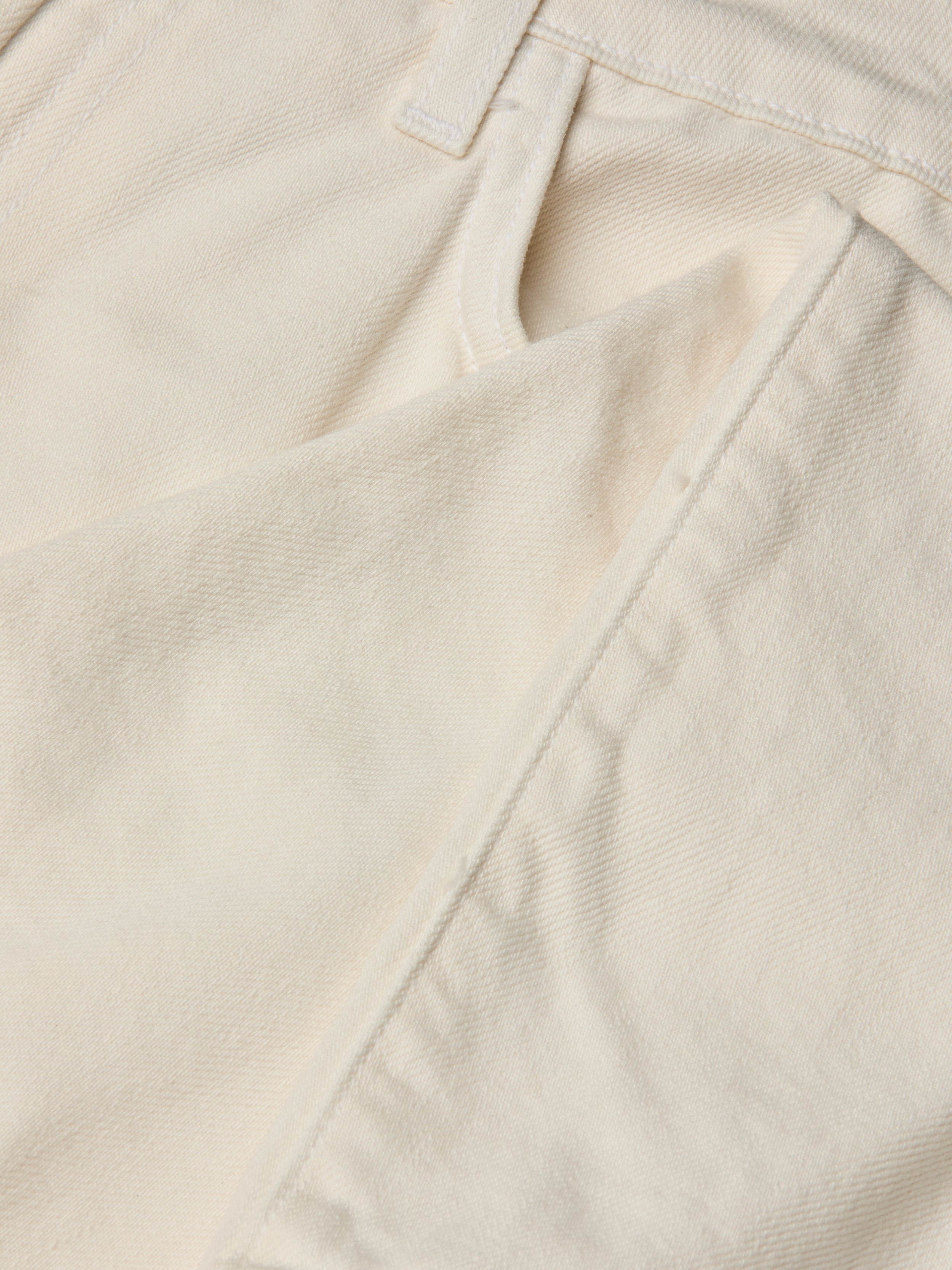 Close-up of the front pocket and waistband of the Blaine Cropped Stovepipe Jean in cream-colored all-cotton denim, highlighting the fabric’s texture, precise stitching, and part of a belt loop.